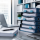 Blue office binders and paperwork stacked beside a laptop on a modern office desk