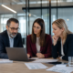 Three business professionals review supplier risk documents and a laptop in a modern office meeting.